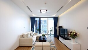 A modern living room with a sofa, coffee table, TV, and a decorative vase. - 3 bedroom in Metropolis near Lotte, Dao Tan (Hanoi)