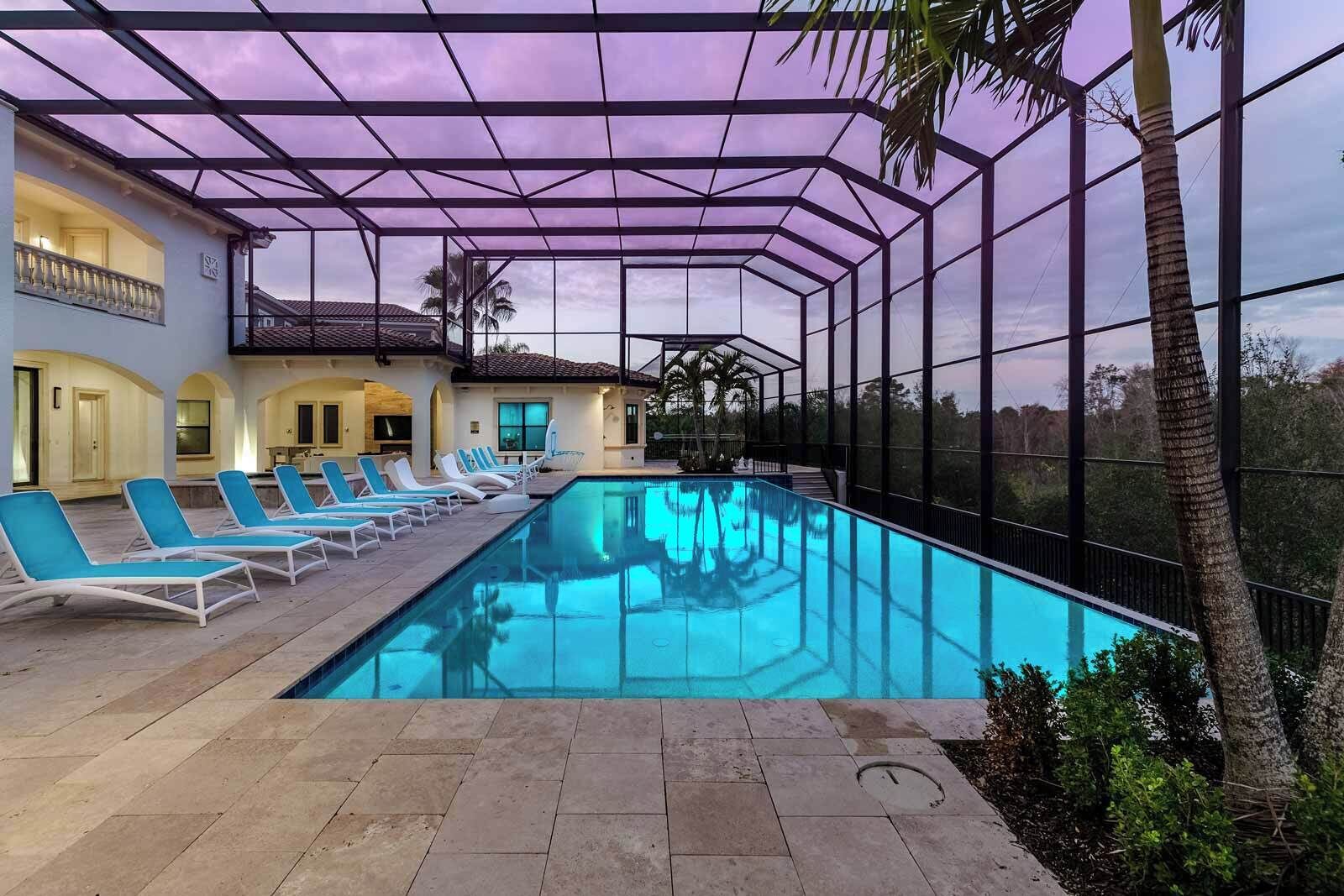 Ein Schwimmbecken mit Liegestühlen, einem überdachten Bereich und Blick auf ein Haus mit Balkon.