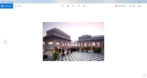 Stroll through a tranquil courtyard surrounded by traditional white arched structures and lush potted plants.