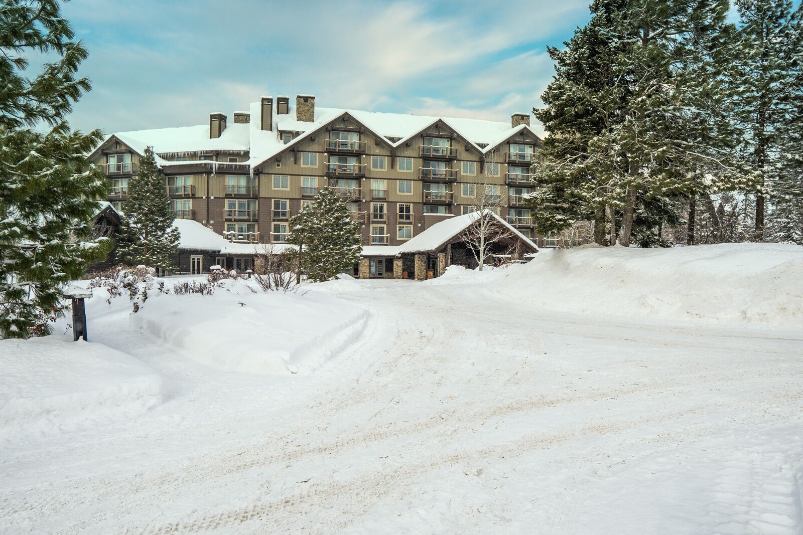 Ein großes Chalet mit mehreren Stockwerken, eine verschneite Landschaft und ein klarer Himmel.
