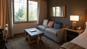 Una habitación de hotel con sofá, una mesita, una lámpara y una cama.