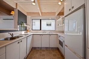 A modern kitchen with white cabinets, a double sink, and a large refrigerator. - Fenworth - Taupo Holiday Home (Taupo Central)
