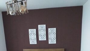 Ein Schlafzimmer mit einem großen Bett, zwei Nachttischen, einem Holzkopfstück und drei Wanddekorationen.