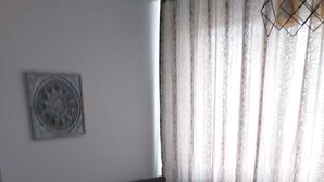 A modern living room with a dark grey sofa, patterned cushions, a small round table, and a decorative wall piece. - Apartment ultracentral (Ploiești)