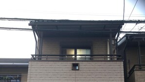 A two-story building with a brick facade, a small window on the upper floor, and a door with a security device. - Near JR AWAJI station <br> 30 min. to Kyoto .10 min. to umeda.<br> 40 min.<br> (Osaka city higashiyodogawa ku)