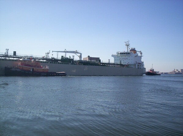 Un gran carguero atracado en un puerto, con un remolcador cerca.