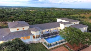 Ein großes, modernes Haus mit Swimmingpool, mehreren Zimmern und einem gepflegten Garten.