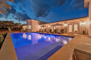 A modern pool area with a clear blue pool, sun loungers, and a covered seating area. - 9000 Sqft Estate/Pickleball/Basketball/Pool/HotTub/9 Bdrm/8 Bath/23Beds/Sleeps35 (Dripping Springs)