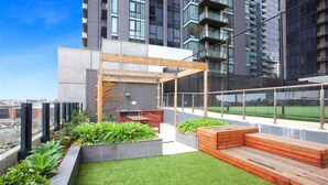 A rooftop garden with a wooden pergola, seating area, and planters. - In the heart of Southbank! (Southbank)
