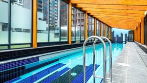 Una piscina interior moderna amb aigua blava cristal·lina, envoltada d'ampies finestres i bigues de fusta.