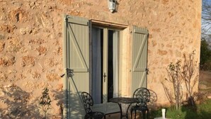 Un edificio de piedra con una puerta y dos sillas afuera.