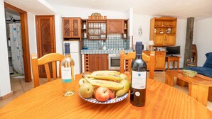 A cozy living room with a wooden dining table, a bowl of fruit, and two bottles of wine. - Casa Rural La Capellania Tenerife, Casa Azul (Granadilla)
