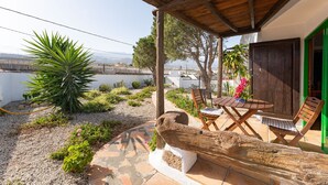A patio with a wooden table and chairs, surrounded by a garden with plants and a large tree. - Casa Rural La Capellania Tenerife, Casa Azul (Granadilla)