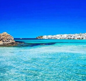A coastal town with white buildings, clear turquoise waters, and rocky outcrops. - Sa Calma Menorca, incredible views of the sea and sunsets (Playas de Fornells)