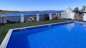 Une piscine offrant une vue dégagée sur la mer et une île au loin.