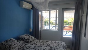 A bedroom with a bed, a window with curtains, and a view of the outside.