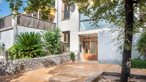 A courtyard with a stone wall, potted plants, and a wooden door. - Apartment Carla near the beach with spacious balcony, mountain view, Wi-Fi & air conditioning (Puerto de Soller)