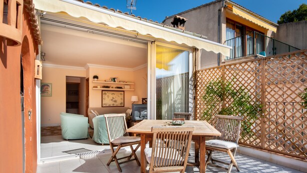 An outdoor patio with a wooden table and chairs, a sliding glass door leading to an interior room, and a wooden lattice fence. - Apartment Carla near the beach with spacious balcony, mountain view, Wi-Fi & air conditioning (Puerto de Soller)