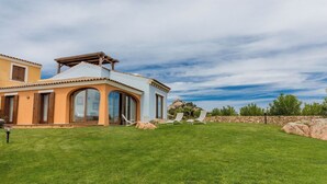 A two-story house with a large lawn, a pergola, and a view of a rocky hill. - 4 km from Porto Cervo with panoramic terrace (Abbiadori)