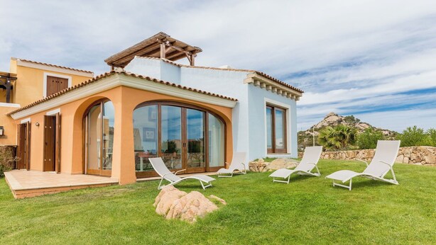 A modern house with a patio, large glass doors, and a view of a mountain. - 4 km from Porto Cervo with panoramic terrace (Abbiadori)