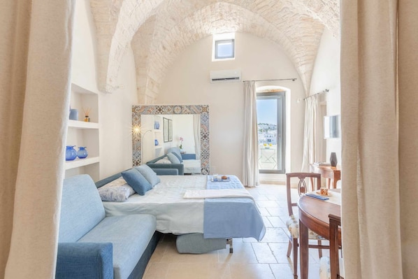 A cozy room with a sofa, a dining table, and a view of the outdoors. - Sea view terrace - outdoor kitchen - outdoor shower - close to parking lot (Ostuni)
