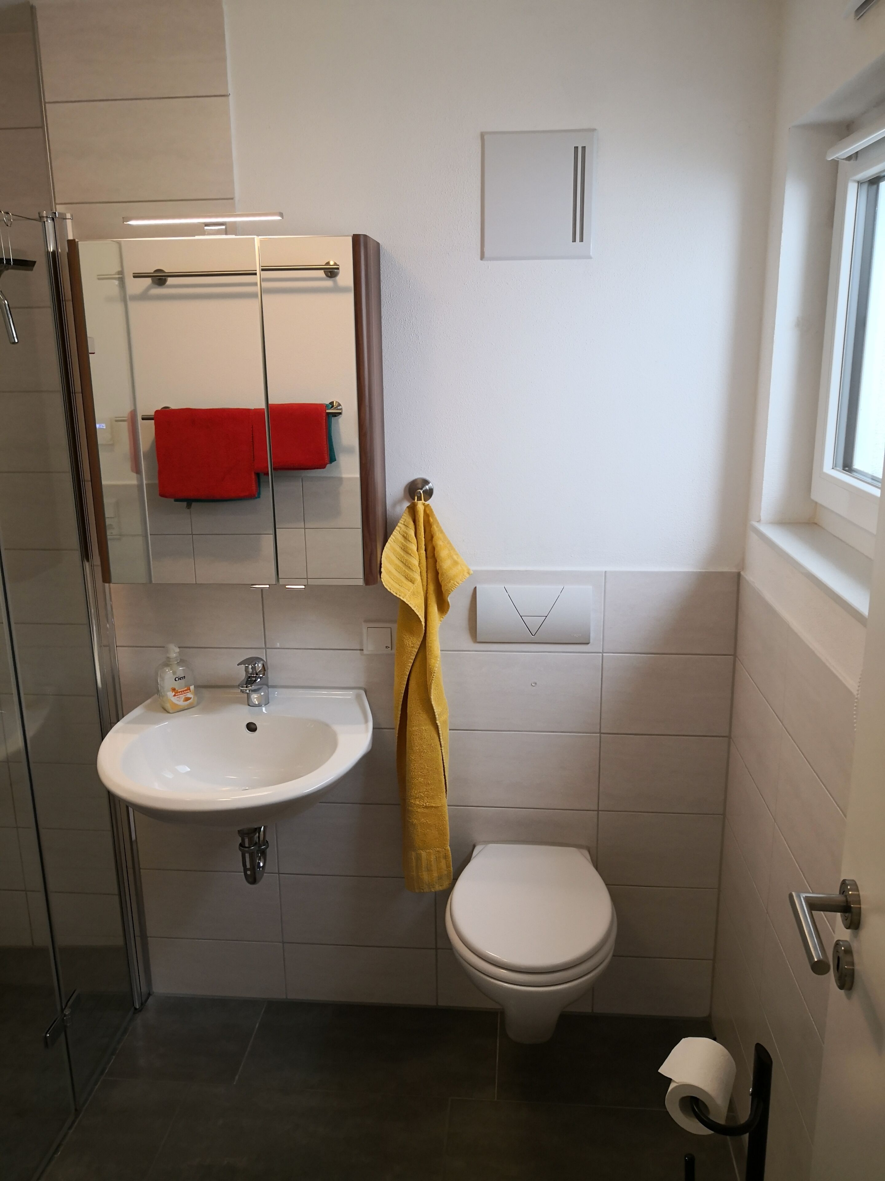 Un bagno con un lavandino bianco, un water, una cabina doccia in vetro e uno specchio.