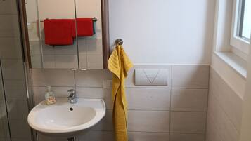 Un bagno con un lavandino bianco, un water, una cabina doccia in vetro e uno specchio.