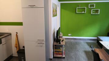 Een keuken met een witte koelkast, een houten tafel en een groene wand.