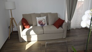 Un salon avec un canapé beige, un lampadaire et une plante en pot.