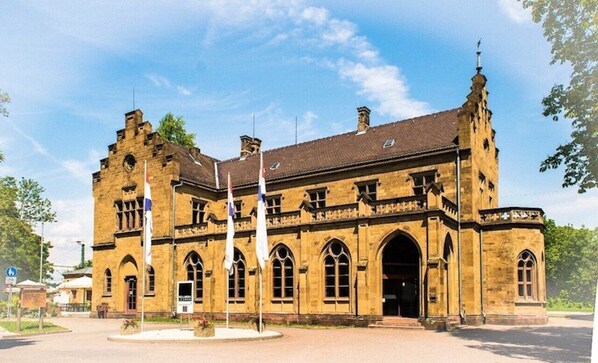 A historic building with a central arched entrance, multiple windows, and a prominent tower with a spire.