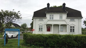 Uma casa branca de dois andares com uma porta vermelha e uma caixa de correio com o número 15.