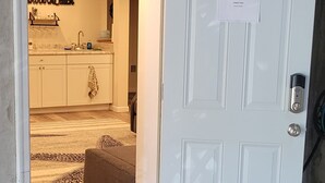 A partially open door to a room with a kitchen area visible, a welcome sign, and a doormat. - Private Basement Suite Near Rehoboth & Lewes (Rehoboth Beach)
