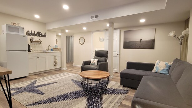 A modern living room with a grey sofa, a wooden coffee table, and a patterned rug. - Private Basement Suite Near Rehoboth & Lewes (Rehoboth Beach)