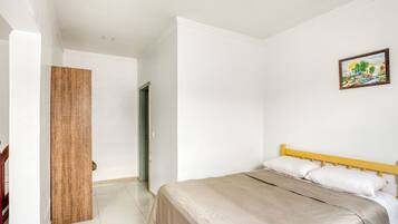 Quarto com cama, porta de madeira e um quadro na parede.