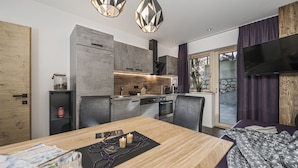 A modern kitchen with a dining area, a TV, and a large window. - 2 bedrooms, kitchen, bathroom, next to the valley run and the valley station (Kaltenbach)