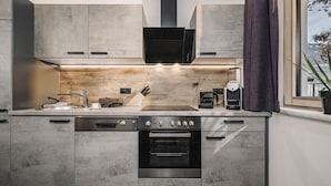 A modern kitchen with a built-in oven, a stovetop, and a sink. - 2 bedrooms, kitchen, bathroom, next to the valley run and the valley station (Kaltenbach)
