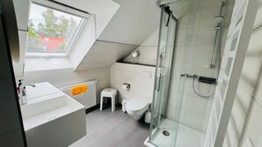 A modern bathroom with a skylight, a shower, a toilet, and a small stool. - Leuchtturmstraße house 17, only 100 m from the Baltic Sea - Leuchtturmstraße (Rerik)