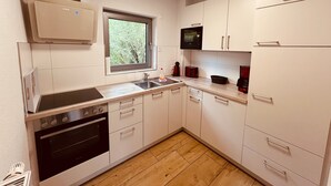 Eine kompakte Küche mit weißen Schränken, einem Backofen, einer Mikrowelle und einem Spülbecken.
