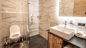 Une salle de bain moderne avec une douche à parois de verre, des toilettes blanches et un meuble-lavabo avec un évier et un miroir.