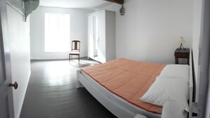 A bedroom with a bed, a chair, and a window. - Country house in country stone (Landrichamps)