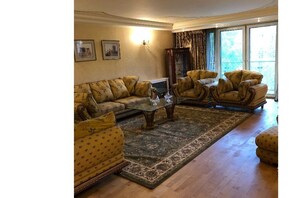 Classic living room with a large coffee table, two sofas, two armchairs, and a patterned rug.
