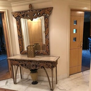 Classic elegance abounds in this refined room, featuring a large mirror above a console table with a decorative vase.