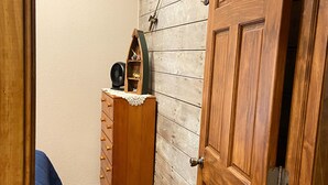 A narrow hallway with a wooden wardrobe, a small wooden shelf with a fan, and a blue bed. - Trout Cove Cabin - Fish, Hike & Relax all in one setting just North of Decorah (Decorah)