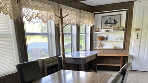 A dining area with a granite table, leather chairs, lace curtains, and a welcome sign. - Trout Cove Cabin - Fish, Hike & Relax all in one setting just North of Decorah (Decorah)