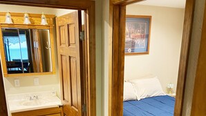 A bedroom with a bed, a nightstand, and a painting on the wall. - Trout Cove Cabin - Fish, Hike & Relax all in one setting just North of Decorah (Decorah)