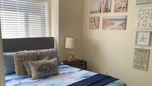 Een slaapkamer met een bed, een plafondventilator, een nachtkastje en decoraties aan de muur.