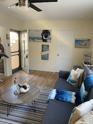 A living room with a gray sofa, a coffee table, and a patterned rug. There are wall art pieces and a ceiling fan. - Hidden gem of Belmont Shores (Long Beach)