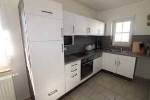 A modern kitchen with white cabinets, a built-in oven, a microwave, and a coffee maker. - Leuchtturmstraße house 15, only 150 m from the beach - Leuchtturmstraße 31 (Rerik)