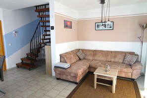 A living room with a brown sofa, a wooden coffee table, a staircase, and a wall-mounted picture. - Leuchtturmstraße house 15, only 150 m from the beach - Leuchtturmstraße 31 (Rerik)