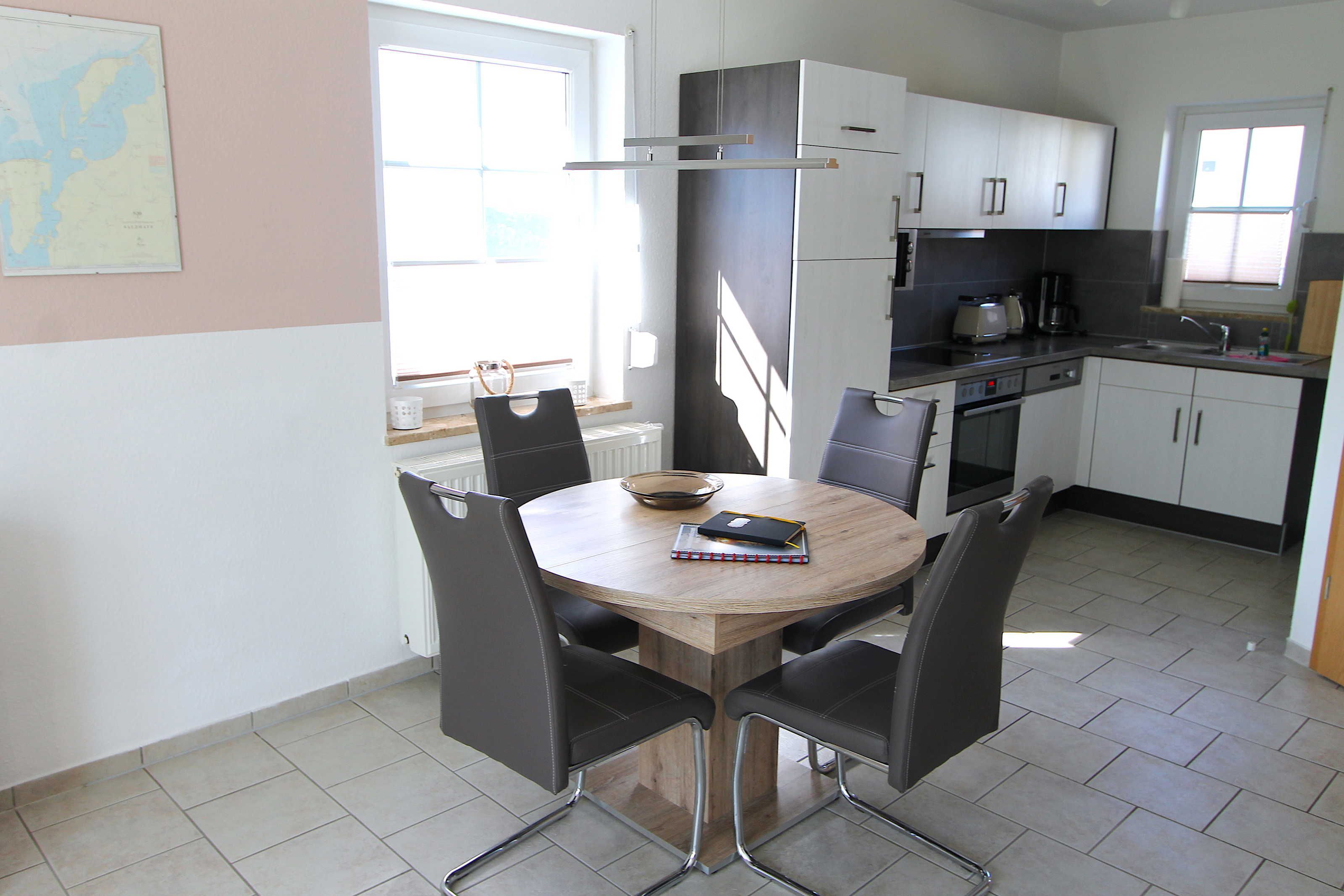 A modern kitchen with a dining table, chairs, and basic appliances.